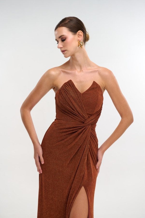 Κοντινό στο μπούστο: strapless ντεκολτέ και ντραπέ κόμπος στη μέση, σε lurex εκάι.