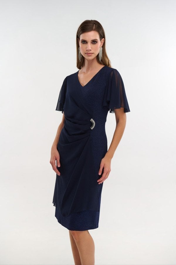 Πλάγια μπροστινή όψη navy blue lurex φορέματος με αγκράφα strass και βολάν μανίκια μουσελίνας.